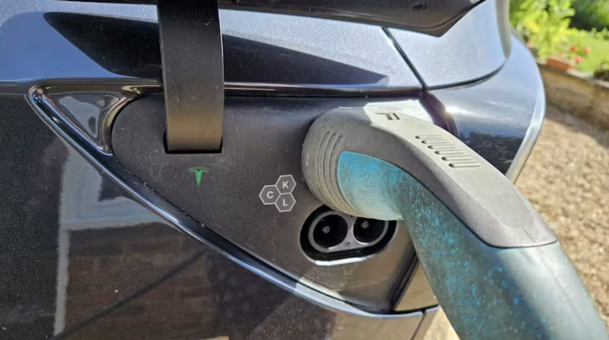 tesla electric car charge port with charger plugged in